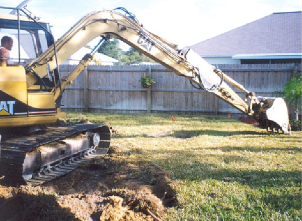 Tractor digging a hole in a backyard