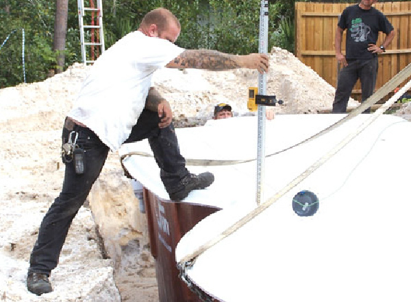 Worker measuring the depth of a pool that's being installed