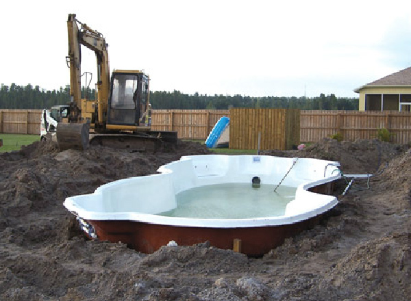 Fiberglass pool being installed in a backyard