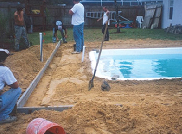 Workers putting in the foundation for the concrete patio that will go around a newly installed pool