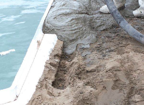 Concrete being poured around an inground pool